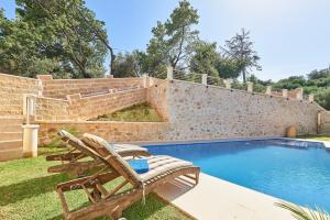 a pool with a bench and a chair next to a wall at Sunaktis luxury villa in Chania
