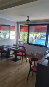 a dining room with two tables and chairs and windows at Hotel Darda in Kamëz