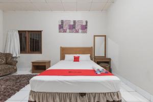 - une chambre avec un grand lit et une couverture rouge dans l'établissement RedDoorz Plus At Hotel Griya Astoeti, à Bogor