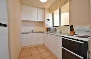a kitchen with white cabinets and a black stove top oven at Riverview Holiday Apartment 47 - Kalbarri, WA in Kalbarri