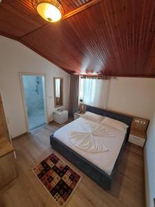 a bedroom with a large bed with a wooden ceiling at Hotel Darda in Kamëz