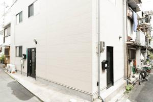 a white building with a black door on a street at 櫻の宿 Sakura Osaka Midoribashi5min 3ppl liubj7 in Osaka