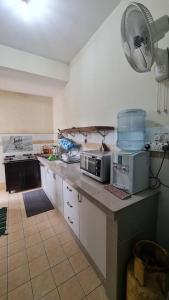 une cuisine avec un comptoir, un four micro-ondes et un ventilateur dans l'établissement Edaman Guest House, à Kota Kinabalu
