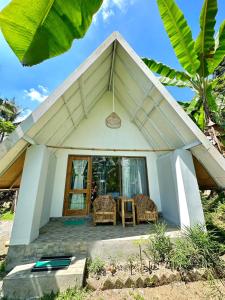 ein kleines weißes Haus mit einem Tisch und Stühlen in der Unterkunft Vanilla Cottage Tetebatu in Tetebatu