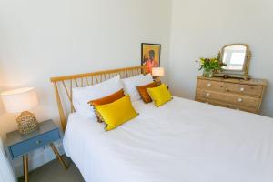 1 dormitorio con 1 cama blanca grande con almohadas amarillas en Treforris, en Rhosneigr