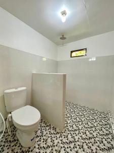 a bathroom with a toilet and a tiled floor at Vanilla Cottage Tetebatu in Tetebatu