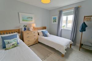a bedroom with two beds and a window at Ty Glan Y Mor in Aberffraw