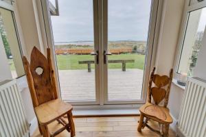 two wooden chairs sitting in front of a sliding glass door at Seaforth in Rhosneigr