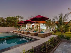a pool with chairs and umbrellas next to a house at Nusa Indah Onai Hotel in Nusa Lembongan