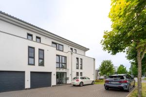 two cars parked in front of a white building at LUXX APARTMENTS I Luxx Central I Design I Komfort in Bad Zwischenahn