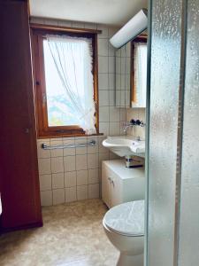 baño con aseo y lavabo y ventana en Chalet Waldwiese - CharmingStay, en Flumserberg