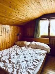 Cama en habitación con techo de madera en Chalet Waldwiese - CharmingStay, en Flumserberg