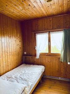 a bed in a wooden room with a window at Chalet Waldwiese - CharmingStay in Flumserberg