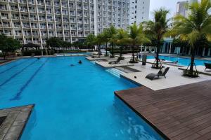 une grande piscine bordée de palmiers et un grand bâtiment dans l'établissement Good Vibes Apartment in Makati, à Manille