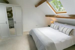 a bedroom with a white bed and a window at Ysgubor Wennol in Llanfairpwllgwyngyll