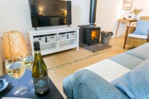 a living room with a bottle of wine and two glasses at Ysgubor Wennol in Llanfairpwllgwyngyll