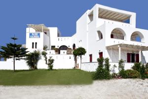 a white house with a palm tree in front of it at Naxos Kalimera Apartments in Agia Anna Naxos