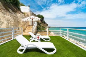two lounge chairs and an umbrella on a balcony overlooking the ocean at Stella Maris in Noto Marina +37 photos