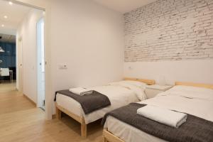 2 camas en una habitación con una pared de ladrillo en Gothic - Ramblas Apartments, en Barcelona