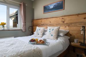 a bed with a bowl of fruit and a plate of food on it at Willow Cottage in Gaerwen