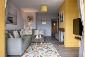 a living room with a gray couch and a tv at Willow Cottage in Gaerwen