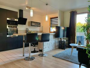 een keuken met zwarte kasten en een tafel en stoelen bij Séjour Business & Famille, 2 chambres, Parking & WiFi in Brétigny-sur-Orge