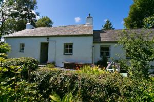una casa blanca con un banco delante en Tyn Llan, en Bodorgan