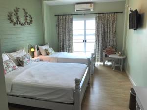 two beds in a room with a window at Khummuangmin Boutique Hotel Nan in Nan