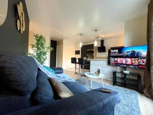 een woonkamer met een blauwe bank en een flatscreen-tv bij Séjour Business & Famille, 2 chambres, Parking & WiFi in Brétigny-sur-Orge +48 foto's