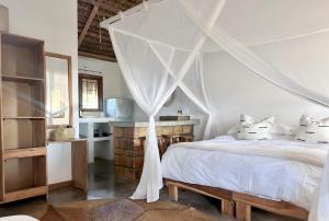 a bedroom with a white bed with a canopy at Blu at tofo in Praia do Tofo