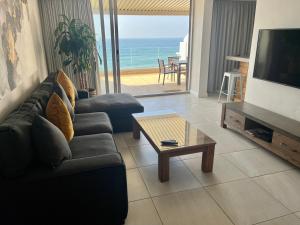 sala de estar con sofá, TV y mesa en 503 Marbella Beachfront Apartment en Durban