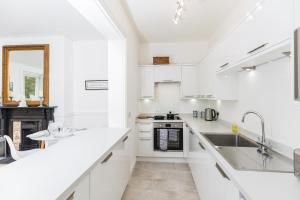 een witte keuken met witte werkbladen en een wastafel bij 20 Montpellier Flat 2 in Cheltenham