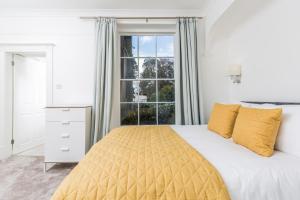 a bedroom with a bed with yellow pillows and a window at 20 Montpellier Flat 2 in Cheltenham