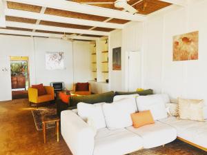 a living room with a white couch and chairs at Deerubbin Boat House in Dangar Island