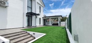 a white house with a yard with green grass at Paddy Farm Cottage 鄉田民宿 (Full Aircon + Karaoke) in Alor Setar