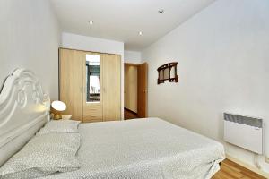 a white bedroom with a large bed and a window at Apartament Sant Feliu in Girona