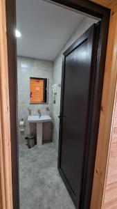 a bathroom with a sink and a black door at Taripiri in Ambrolauri