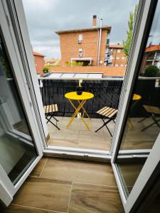 a patio with a yellow table and chairs on a balcony at Nordic Home in Tudela