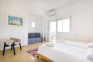 Habitación blanca con 2 camas y silla en Beach Front Villa en Shave Ẕiyyon