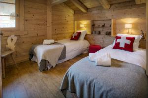 a bedroom with two beds in a log cabin at Chalet Hollygotty - OVO Network in La Clusaz