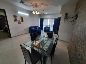 a dining room with a glass table and blue chairs at Staeg Skyline View 3BHK - 1404 in Indore