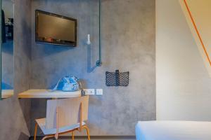 a room with a tv on a wall with a chair at Ibis Budget Lyon Est Saint Quentin Fallavier in Saint-Quentin-Fallavier