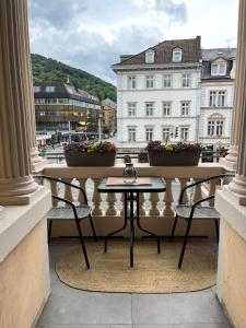 a table and chairs on a balcony with buildings at Denner Hotel in Heidelberg