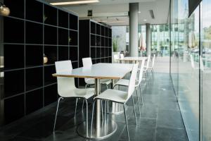 une rangée de tables et de chaises dans une pièce revêtue de carrelage noir dans l'établissement AS Porta de Barcelona, à Castellbisbal