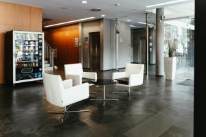 een lobby met witte stoelen en een drankkoeler bij AS Porta de Barcelona in Castellbisbal