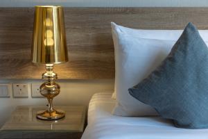 a lamp on a table next to a bed with pillows at Anan Hotel By Snood in Makkah