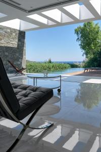 a chair on a patio with a view of the ocean at A - Luxury Villas in Plomarion