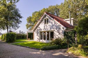 a white house with a brick driveway at KempenLodge, luxe boshuis voor 8 pers, in Brabantse natuur in Diessen