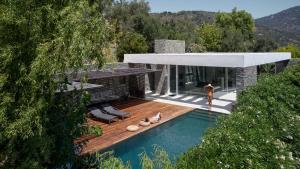 a woman walking past a house with a swimming pool at A - Luxury Villas in Plomarion