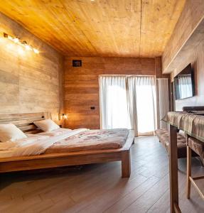 una camera con un grande letto in una stanza con pareti in legno di Alta Luce Mountain Lodge a Gressoney-la-Trinité